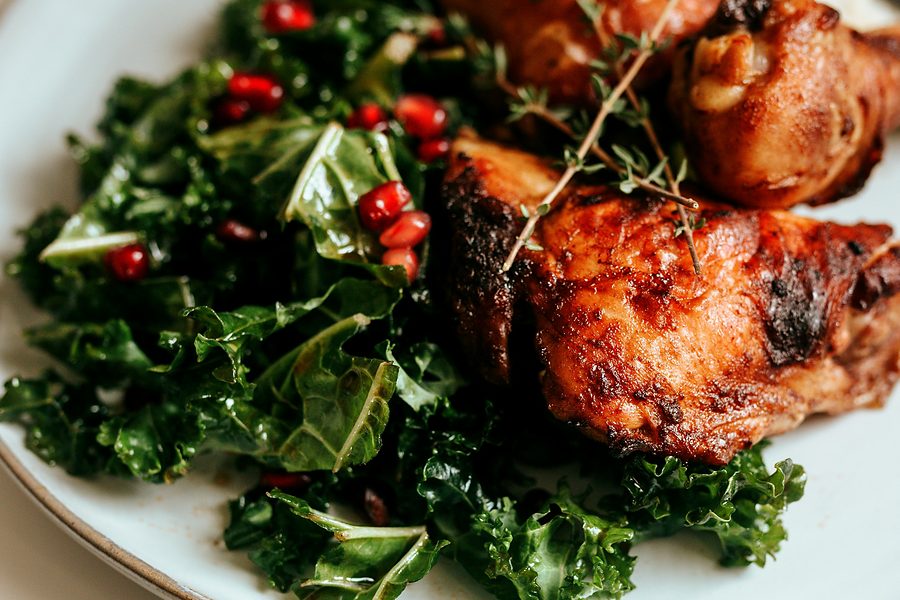 Roasted chicken thighs with greens, on a pale plate