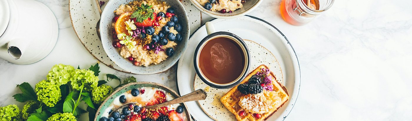 An overhead table of breakfast dishes, bowls of fruit and coffee